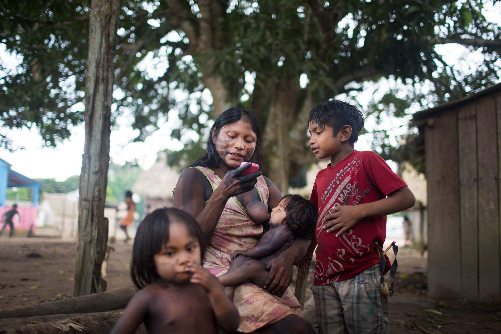 A Xikrin mother listens to music as she breastfeeds her daughter.