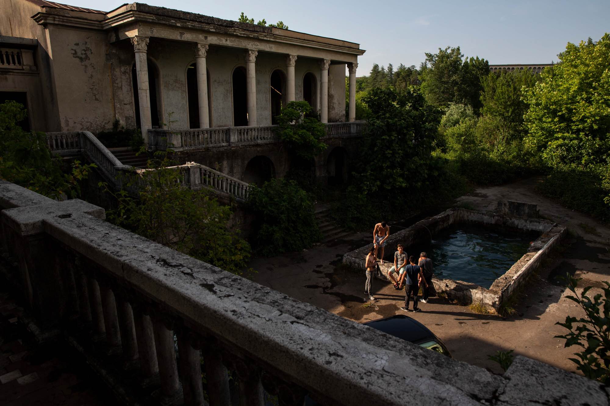 Young men relax by a pool at Sanatorium Medea in Tskatulbo, Georgia on June 15, 2019.