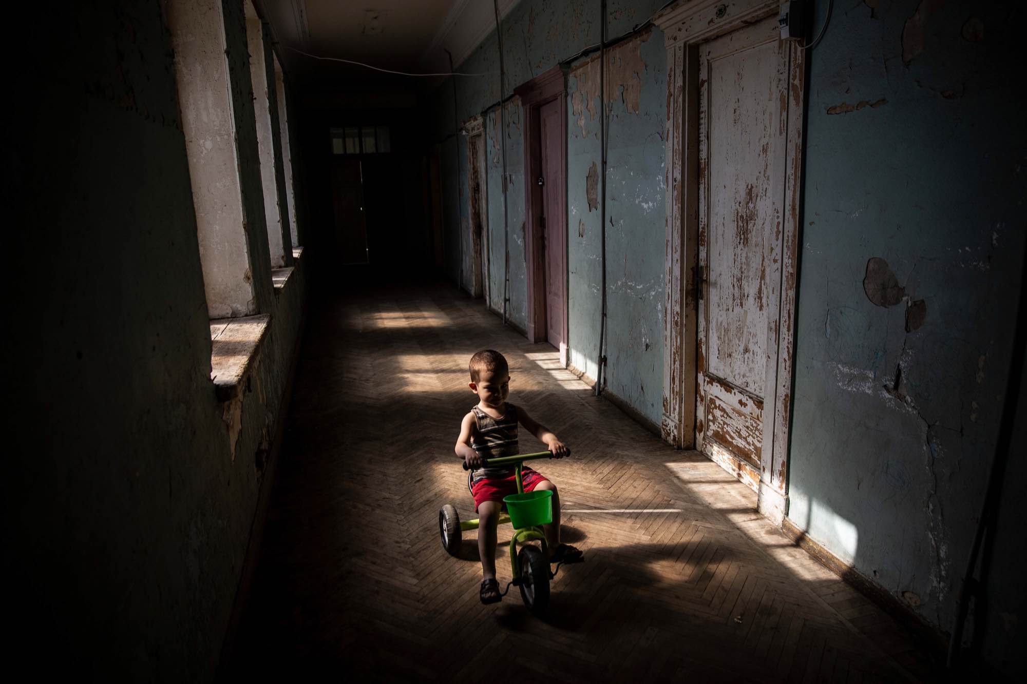 A young boy rides a tricycle down a hallway at Sanatorium Tskaltubo in Tskatulbo, Georgia on June 15, 2019.
