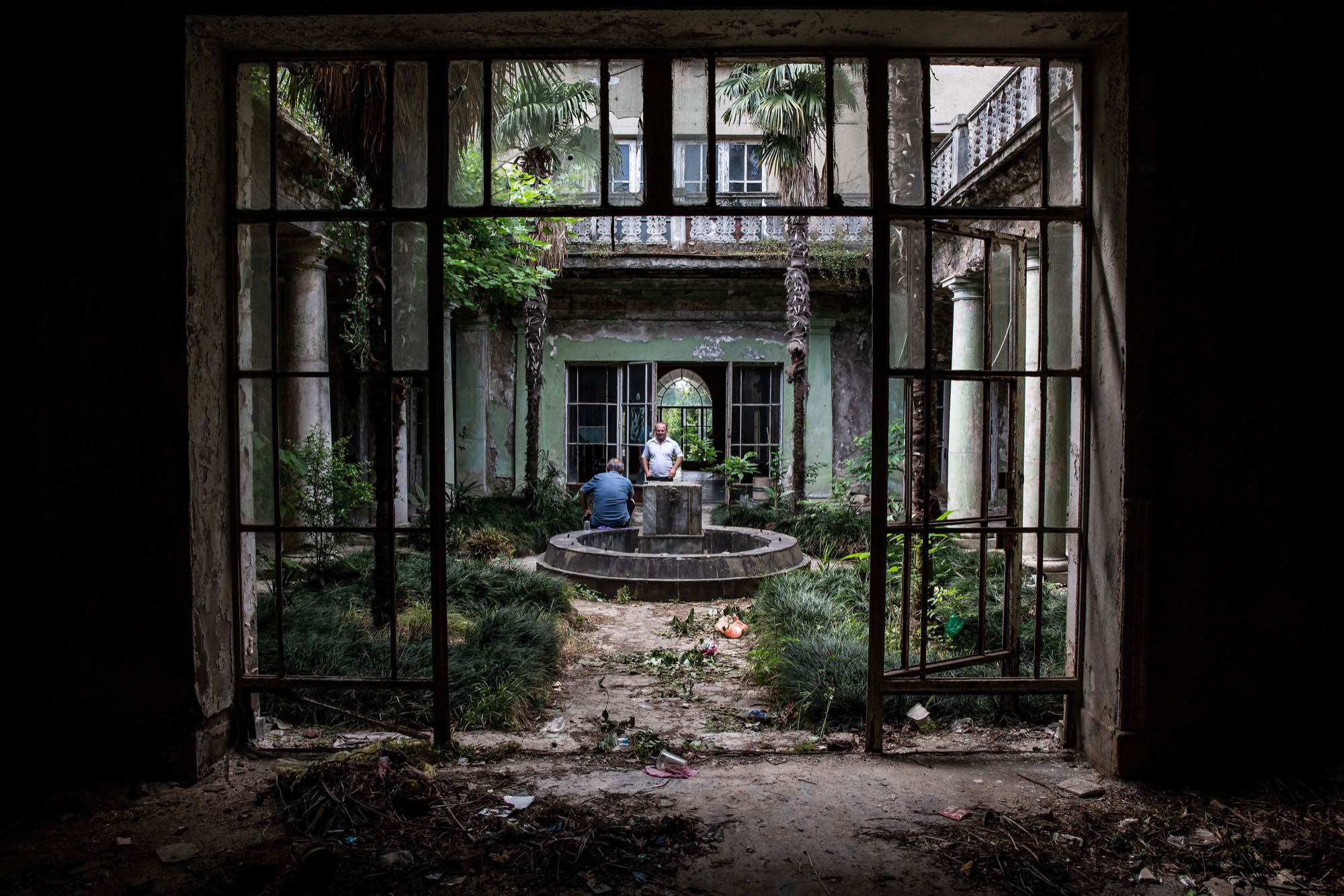Men chat in a courtyard at Sanatorium Tbilisi in Tskatulbo, Georgia on June 16, 2019.