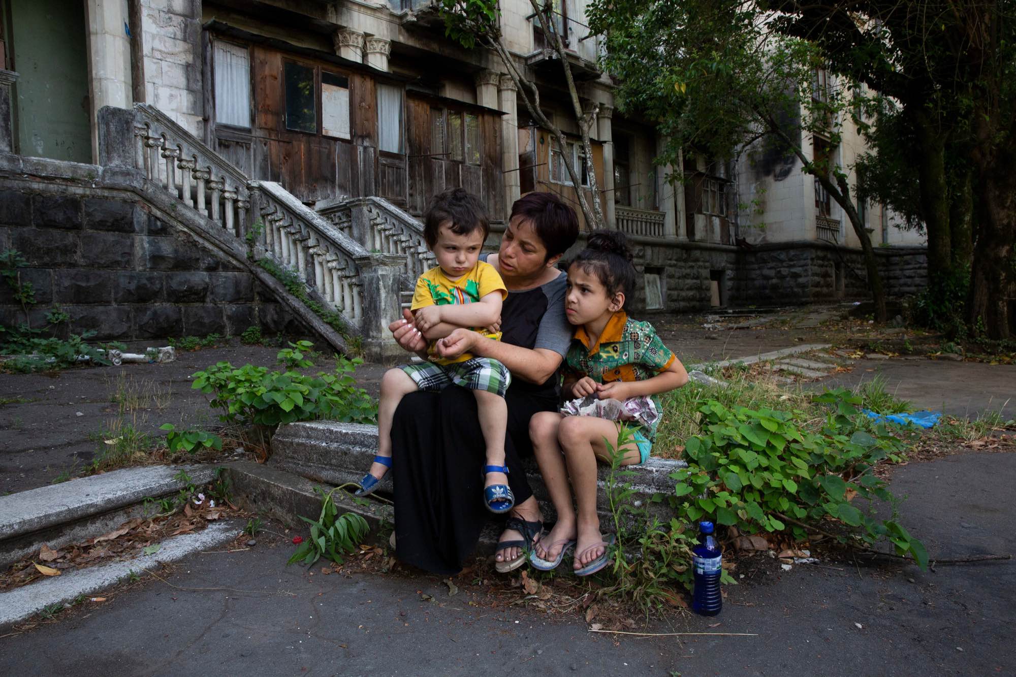 Jana Managadze, 42, sits with her two children outside Sanatorium Medea in Tskatulbo, Georgia on June 15, 2019.
