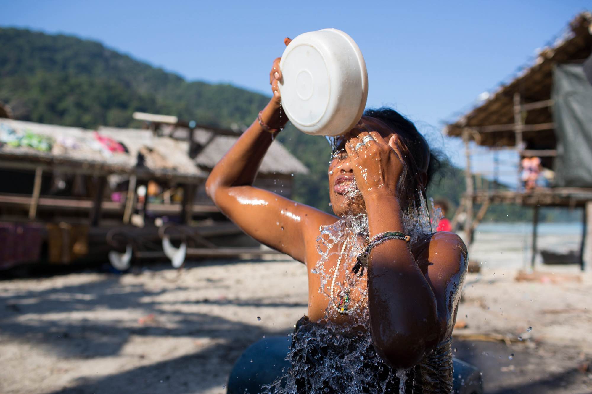 Koh, an indigenous Moken woman, washes her face with freshwater after making charcoal in the jungle.