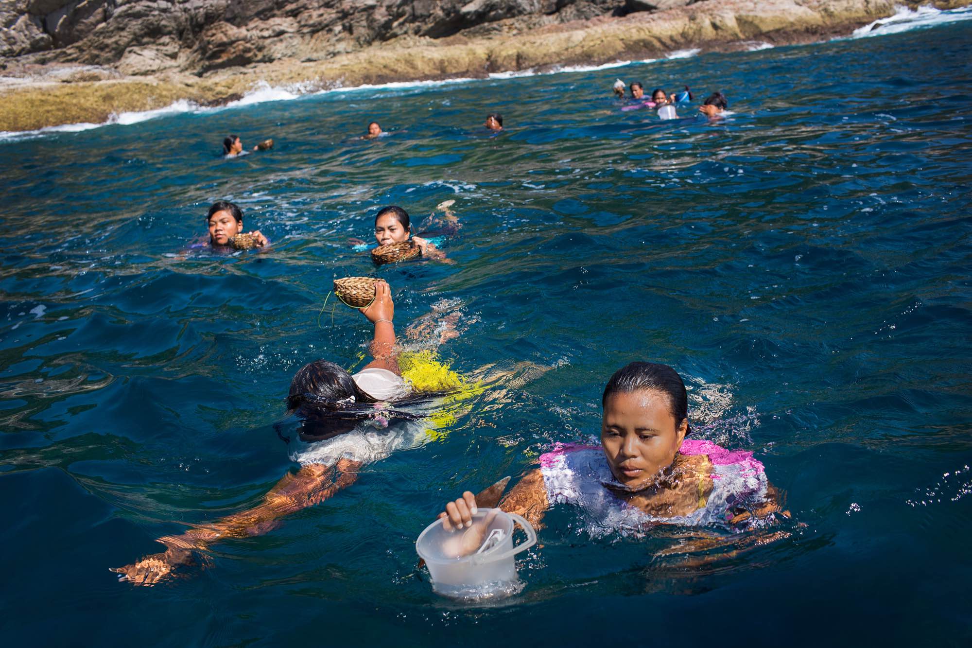 Moken women return to a waiting boat after foraging for food on the rocky shores of the Ko Surin National Park, Thailand.