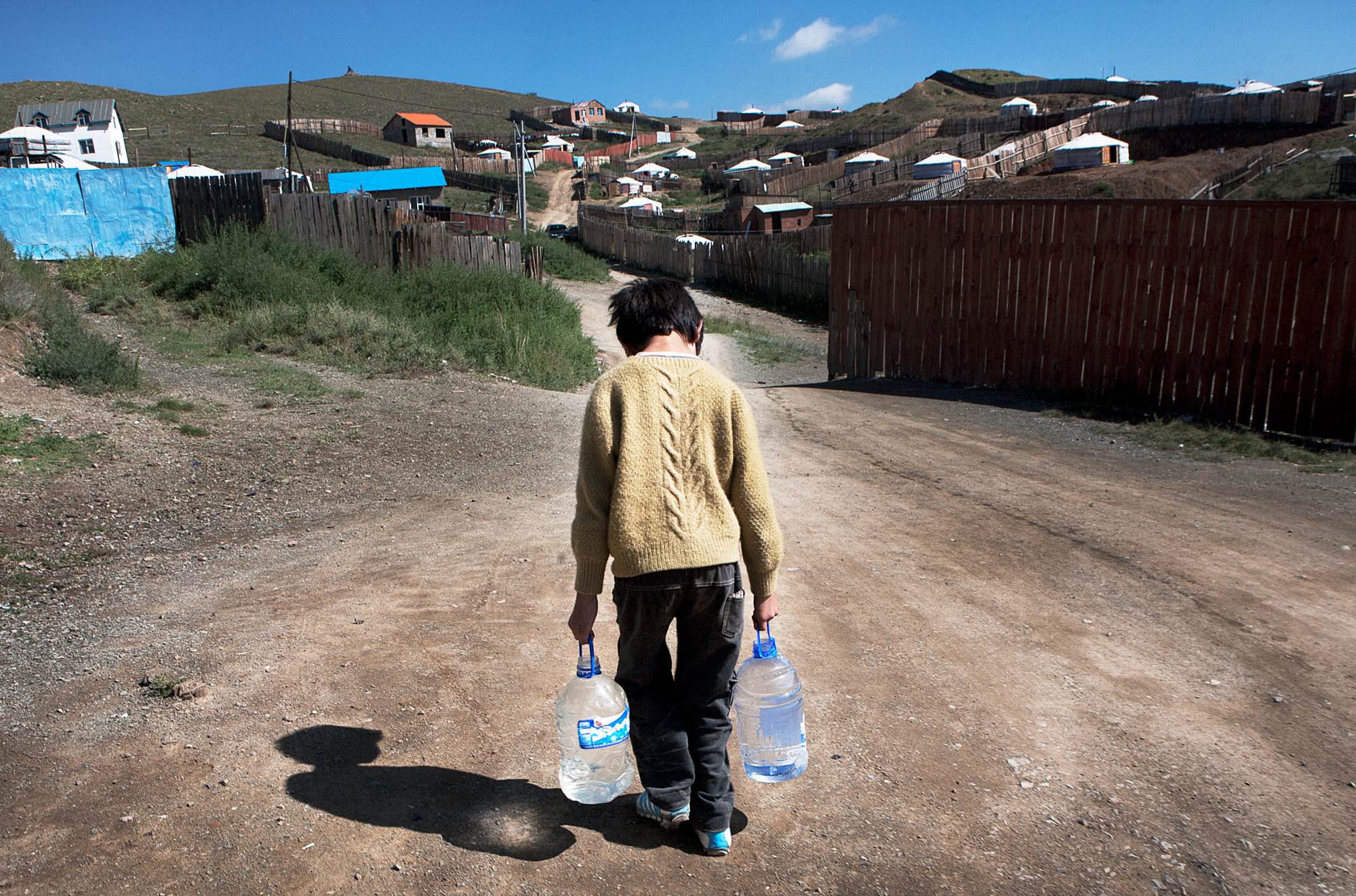 A Mongolian boy brings water to his home in the ger district.