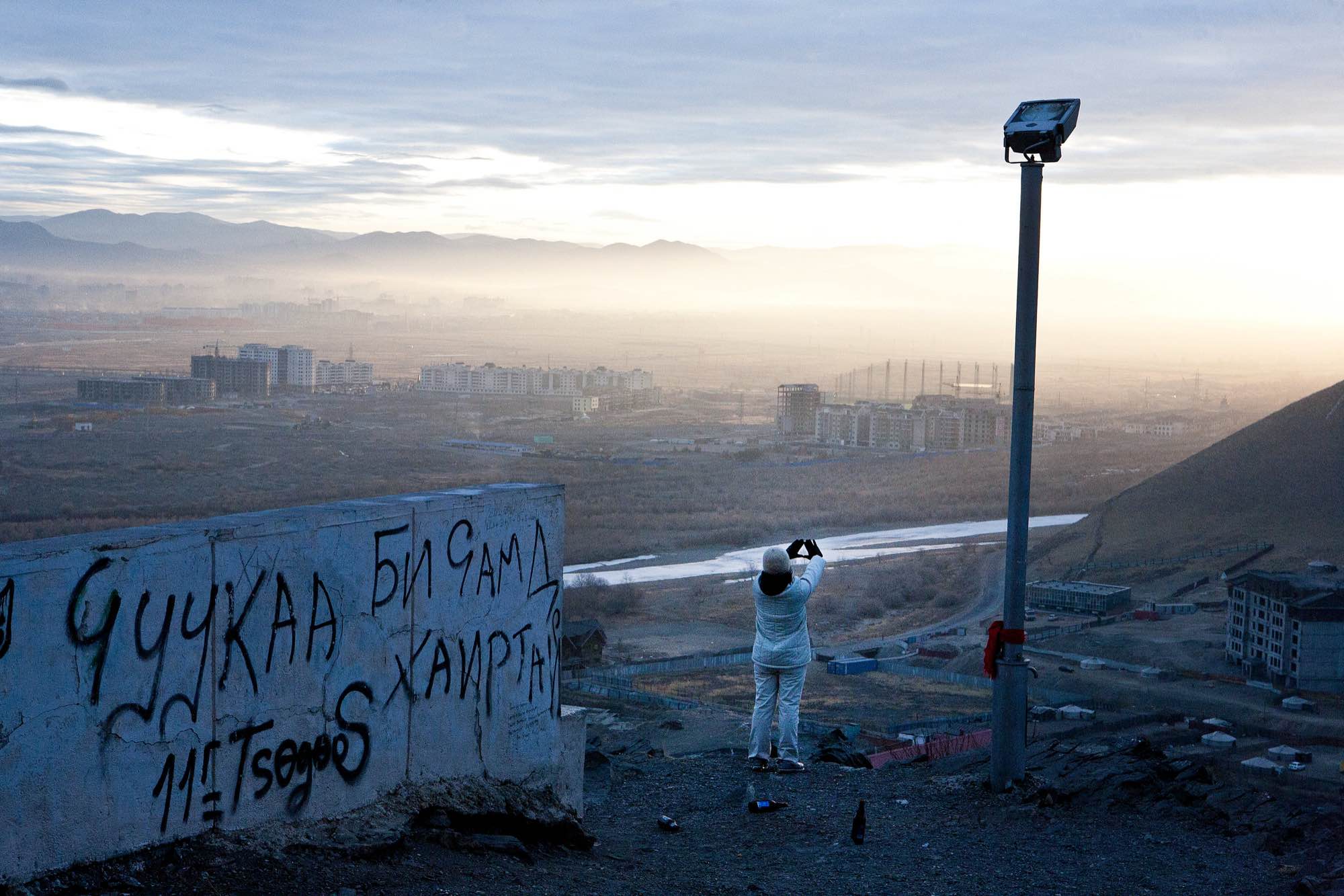 A woman stretches on a hilltop overlooking Ulaanbaatar's sprawl.