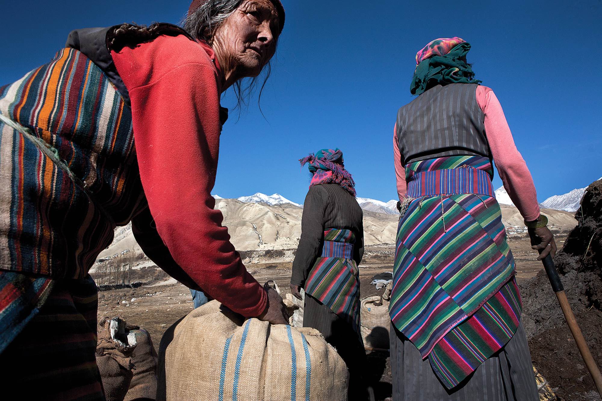Villagers of Phuwa load bags of fertilizer onto horses to be taken to the fields.