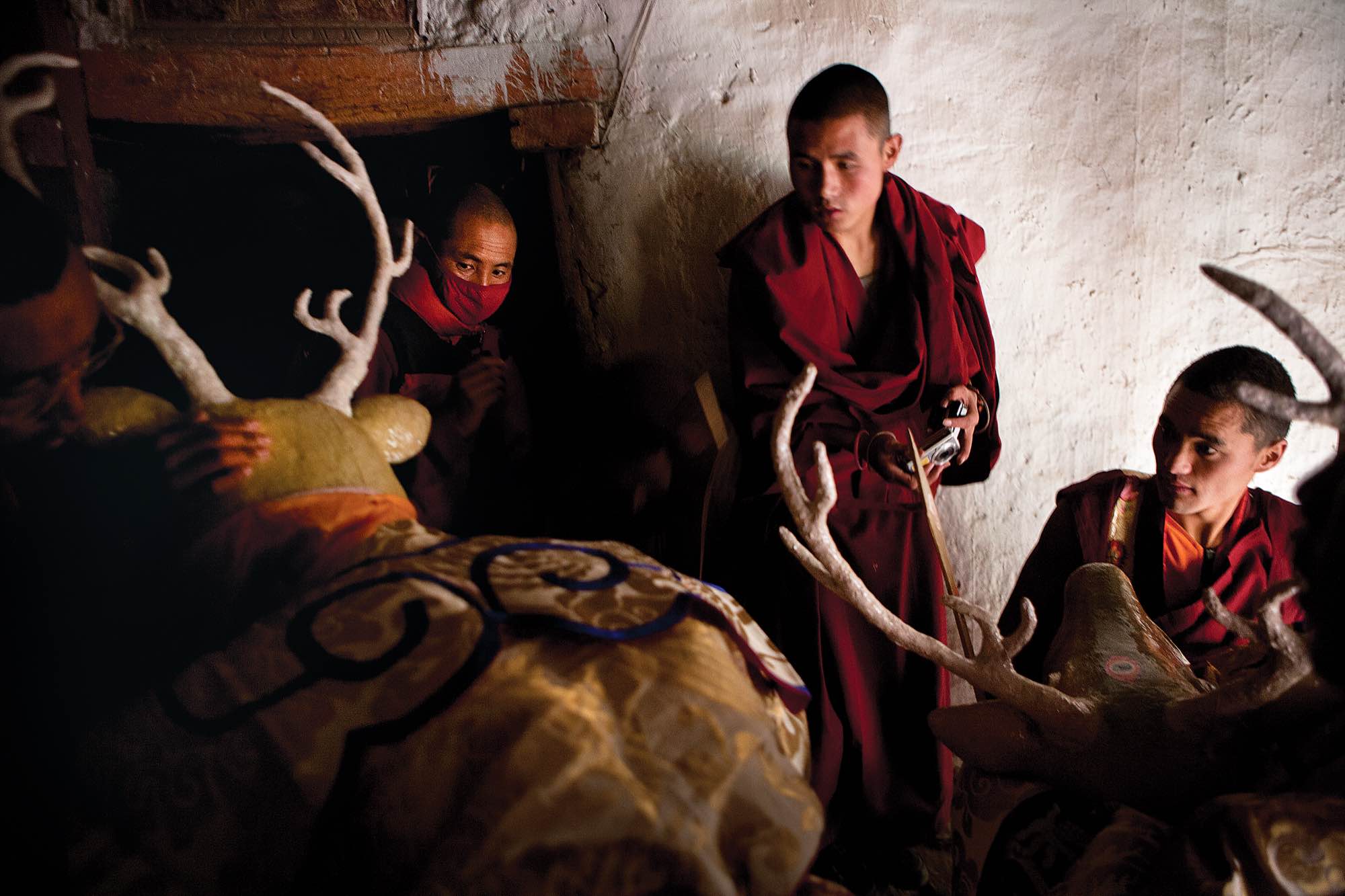 In a staging area inside of the king's palace, a group of monks helps prepare dancers for an upcoming ceremony during the Tiji festival.