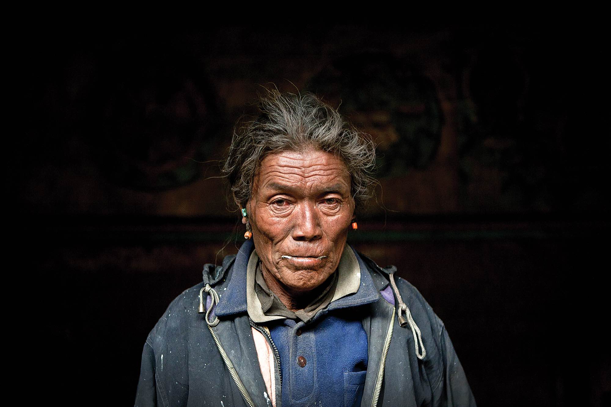 The winter monastery keeper stands for a portrait in the main hall of the monastery in Tetang.