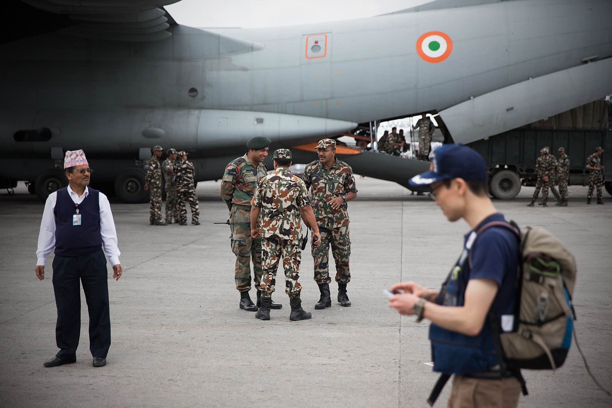 A Japanese aid worker walks past a military plane sent from India arrive at Tribhuvan International Airport in Kathmandu, Nepal on April 29, 2015.