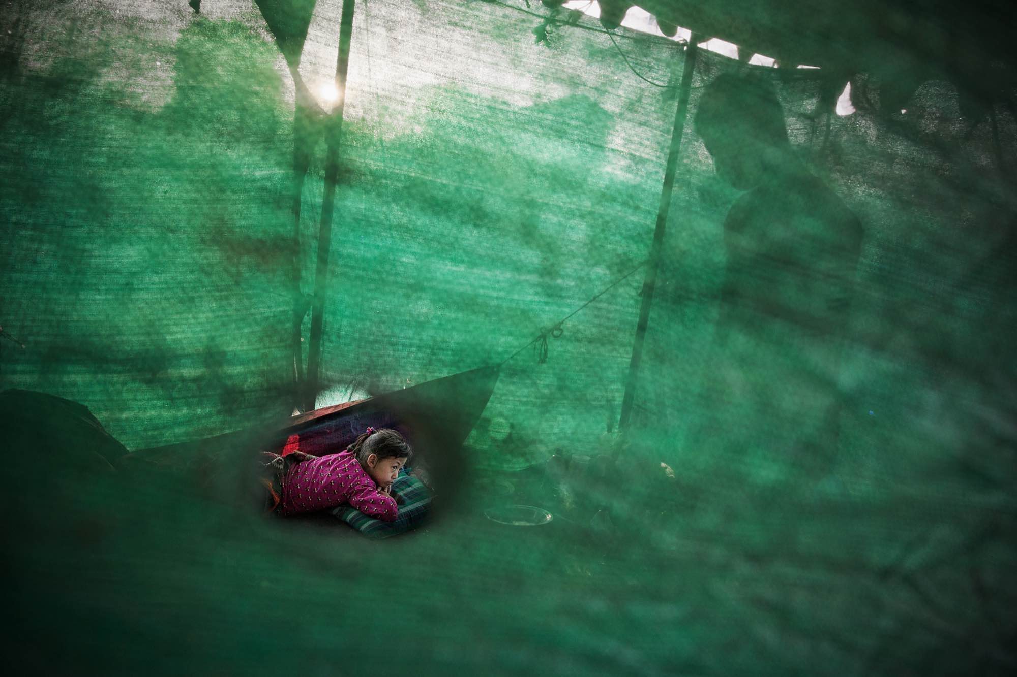 A Nepali girl displaced by the earthquake spends time in her temporary shelter on a field in Kathmandu, Nepal.