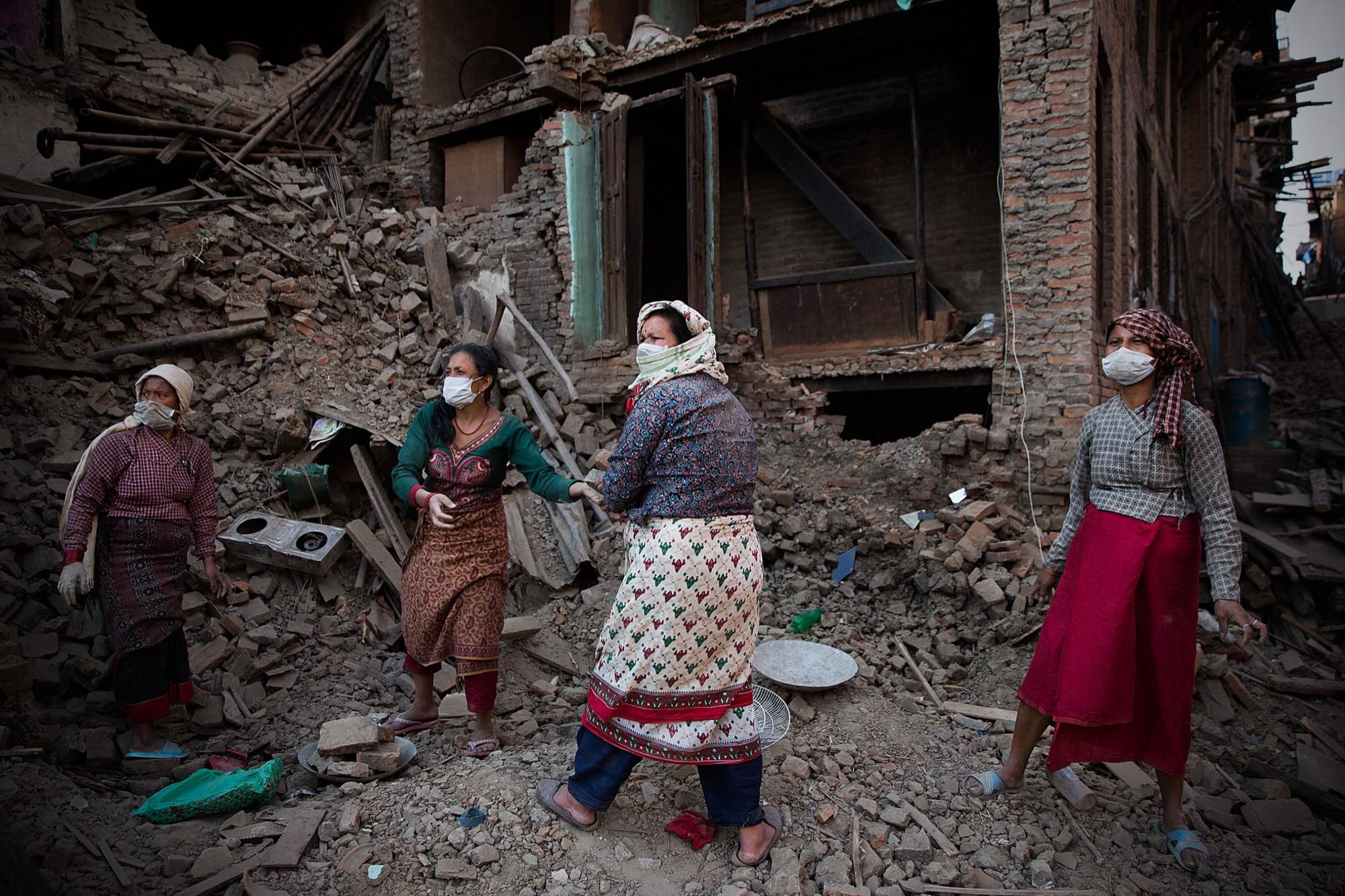 Nepali women comb through the rubble of their devastated home looking for valuables in Bhaktapur, Nepal.