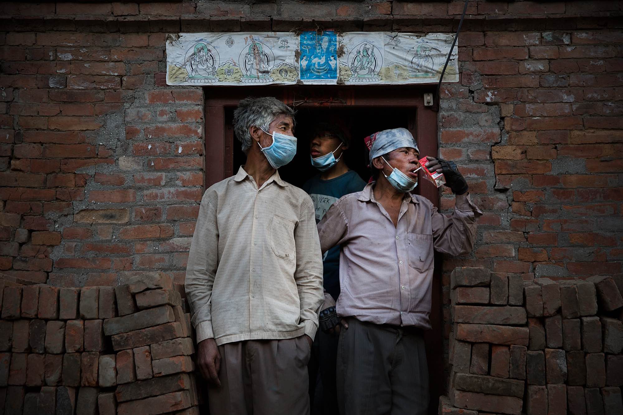 Nepali men take a break from combing through the rubble of their devastated homes looking for valuables in Bhaktapur, Nepal.